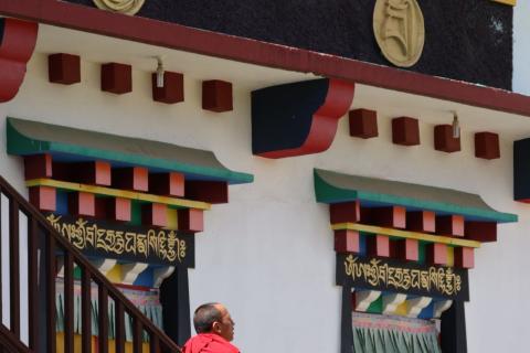 Tibetan-style monastery windows with a monk on the steps, Bir