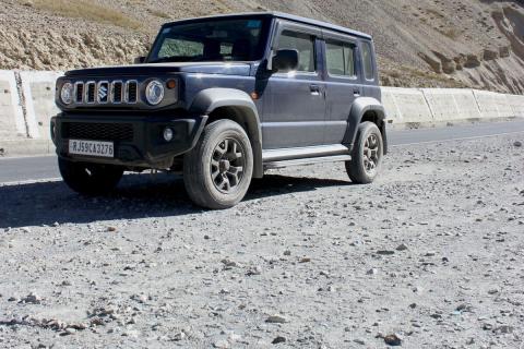 An SUV in the high desert near a Himalayan peak